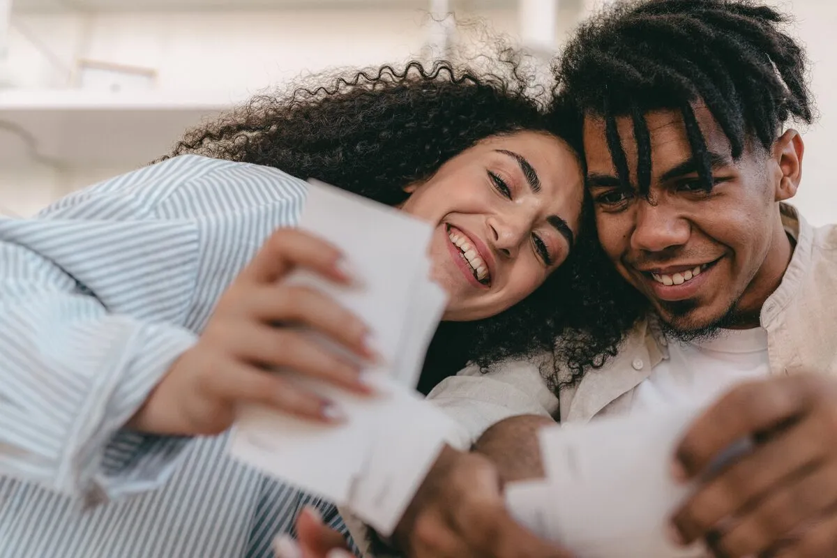 Smiling couple with heads together looking through printed wedding photos