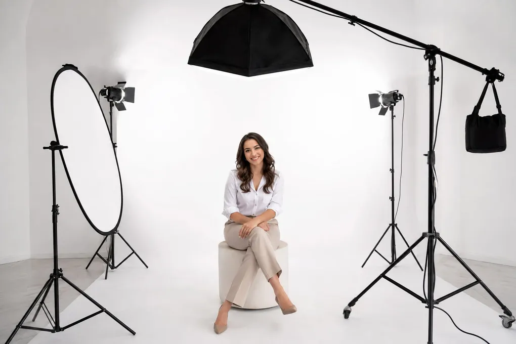 White studio set with an octabox, ring light and strobes surrounding a seated subject for high key lighting