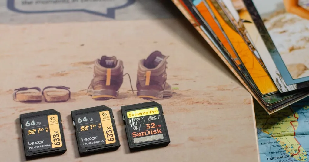 Lexar and SanDisk memory cards on a map beside printed photos and hiking boots, the local files cloud storage for photographers has to back up
