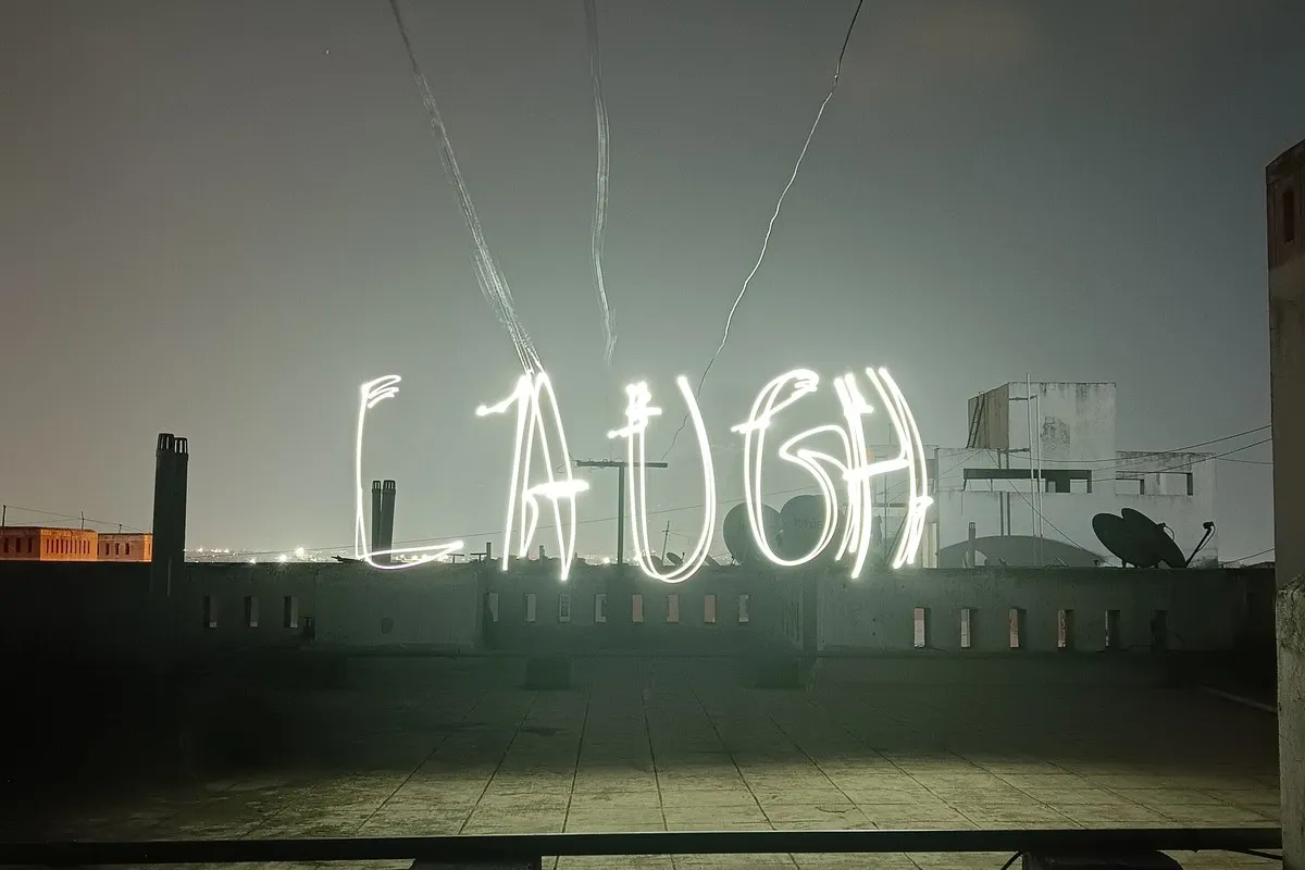 The word LAUGH written in light above a rooftop at night