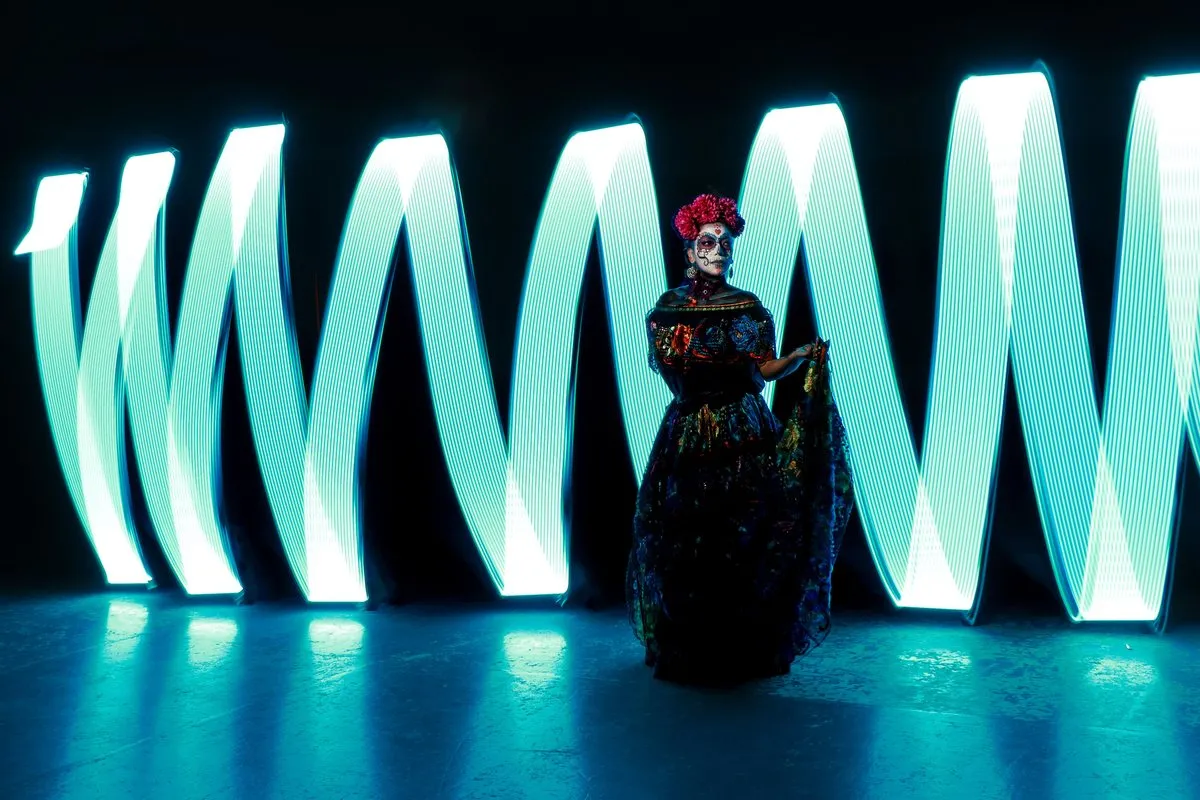A woman lit sharply against light-painted cyan shapes in the dark
