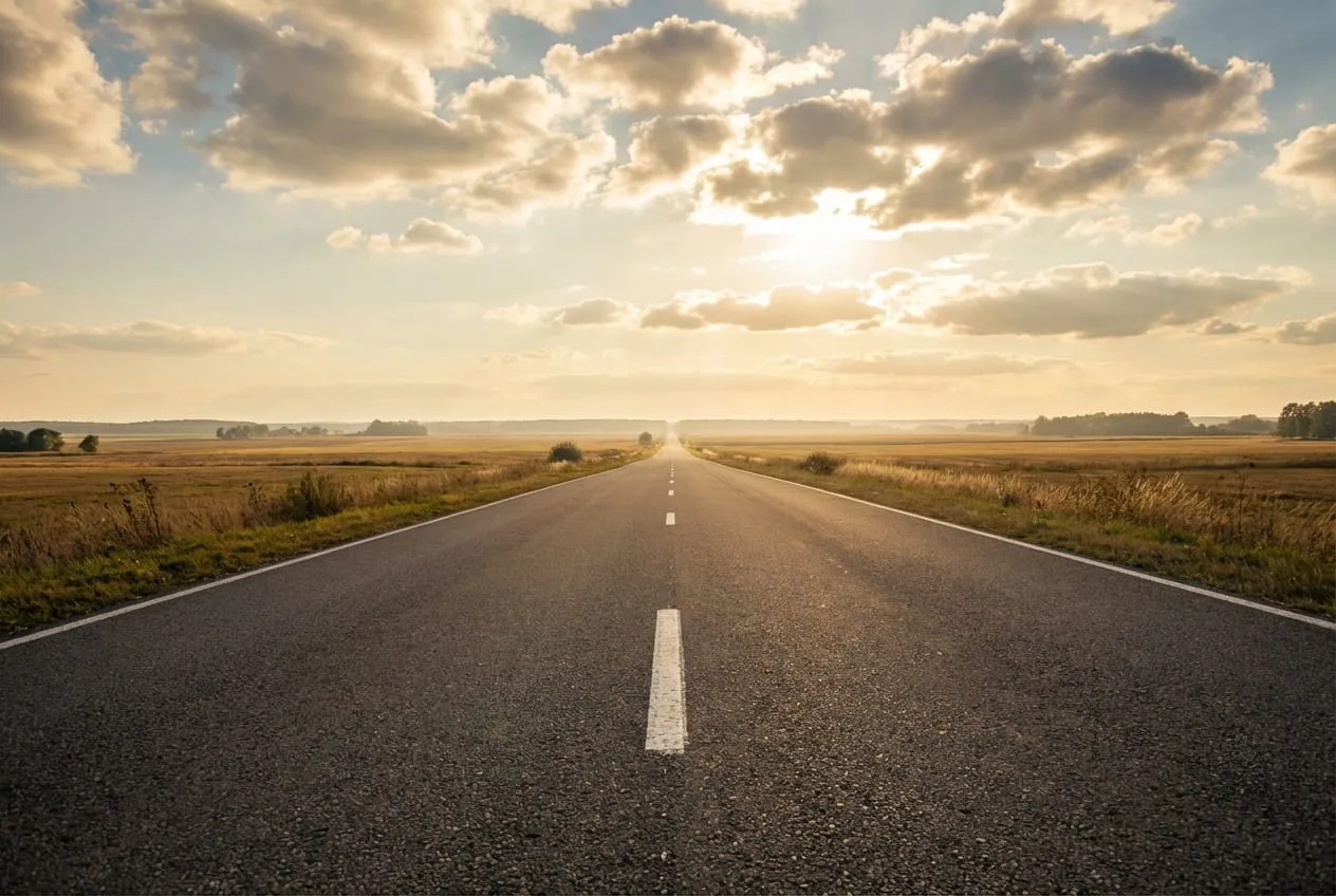 A straight road disappearing to the horizon, its lane markings forming a direct leading line to the vanishing point