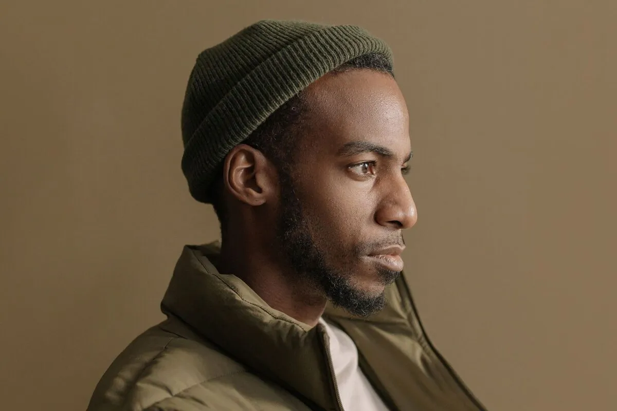 Profile portrait of a man in a beanie looking across open space toward the edge of the frame