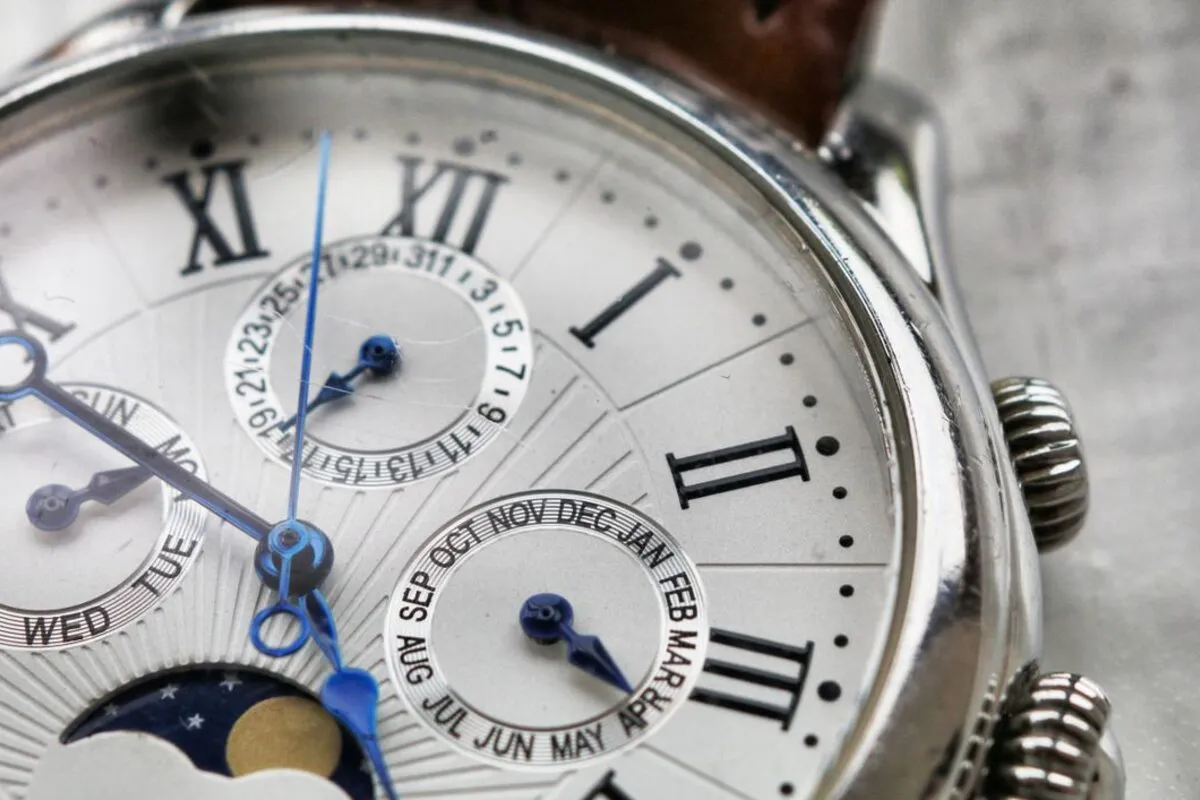 A macro detail shot of a wristwatch dial showing fine texture and lettering